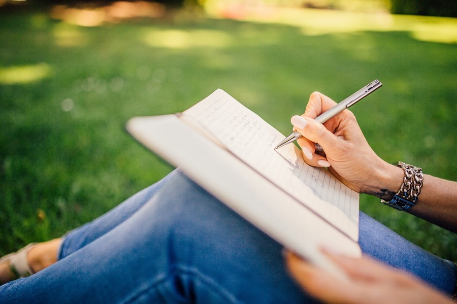 woman on lawn writing in bird watching journal